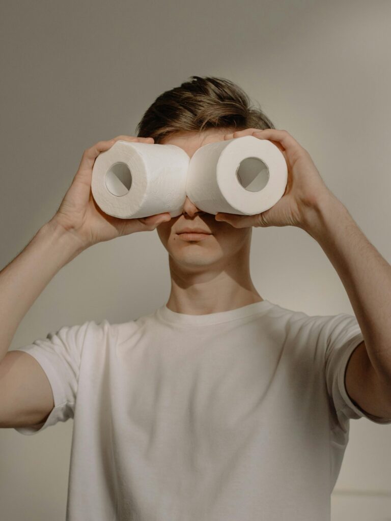 Man using toilet paper as binoculars, displaying humor and creativity